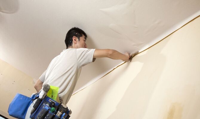 クロスの貼り換え作業を行うスタッフ